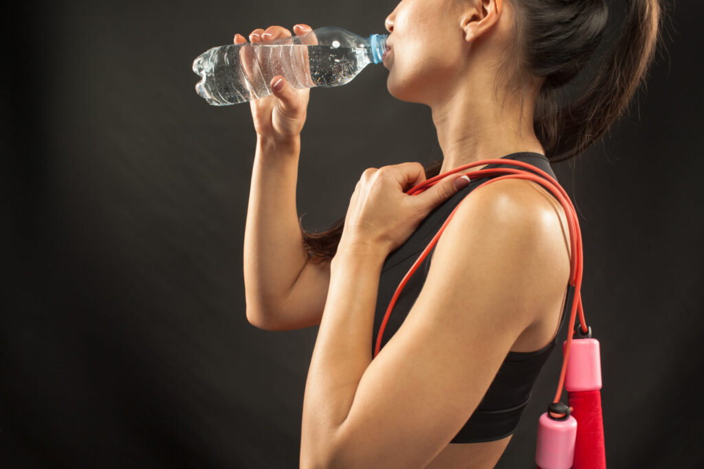 Sportlerin trinkt aus Wasserflasche.