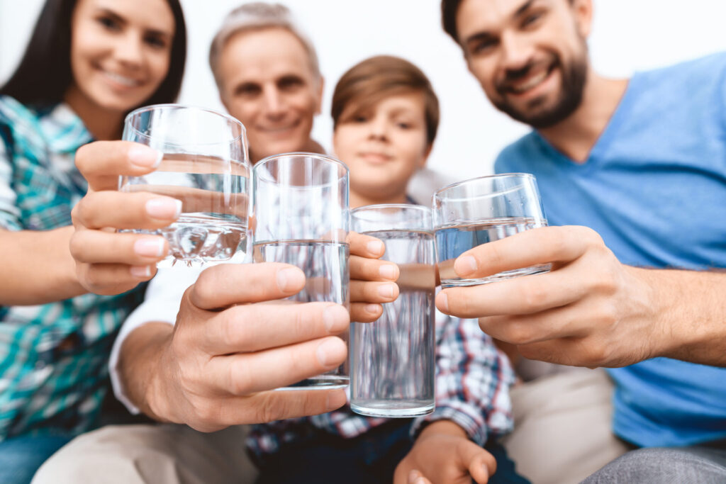 Familie hält Wassergläser in die Kamera.