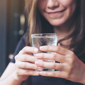 Frau hält Wasserglas in Händen.