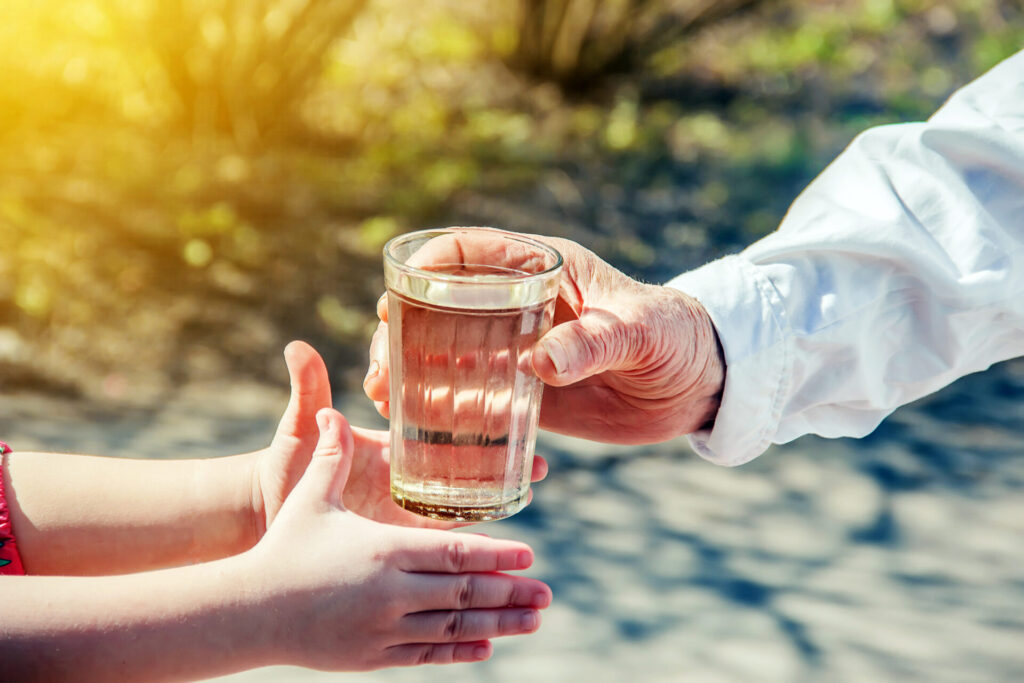 Großmutter gibt Kind ein Glas Wasser.