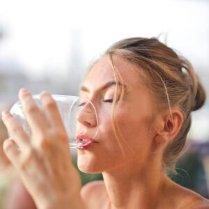 Frau trinkt aus Wasserglas.