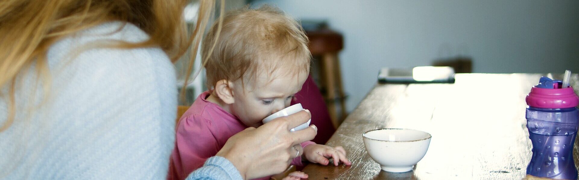 Baby trinkt Wasser aus Tasse.