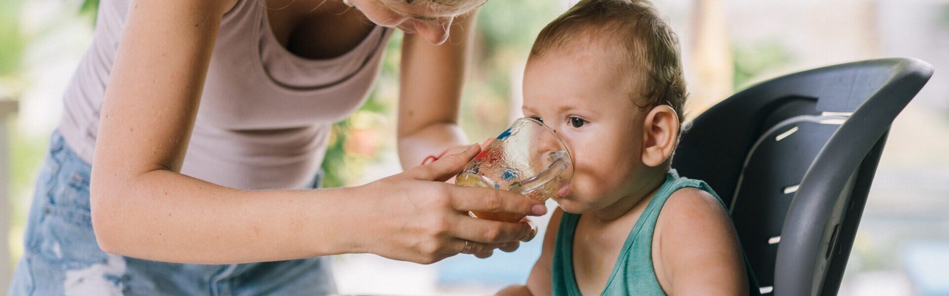 Baby trinkt Wasser aus Becher.