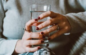 Frau hat ein Wasserglas in den Händen.