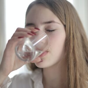 Frau trinkt Wasser aus einem Glas.