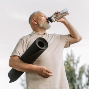 Älterer Herr trinkt aus Wasserflasche nach Sport.