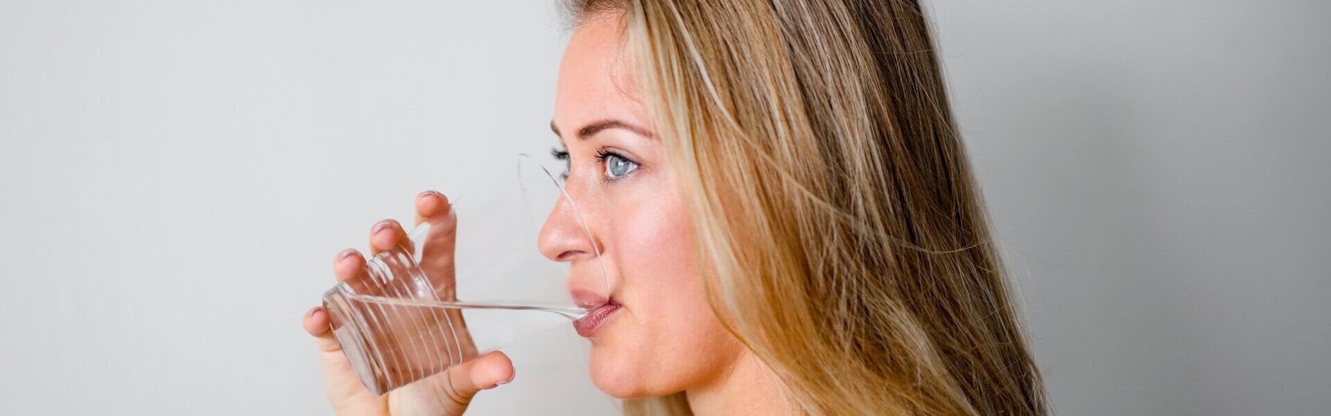 Frau trinkt aus Wasserglas.