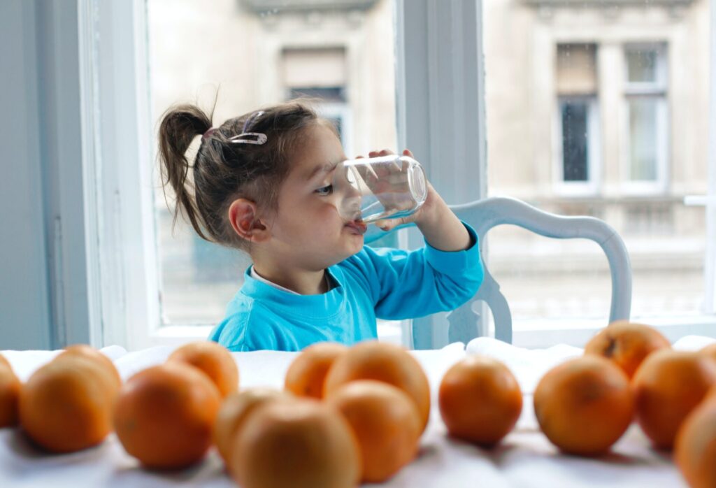 Kind trinkt aus Wasserglas.