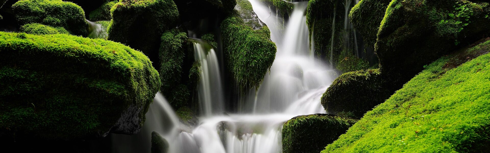 Stimmungsbild: Wasserfall zwischen moosbedeckten Felsen.