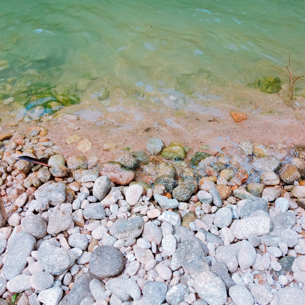 Stimmungsbild: Steinstrand mit türkisem Wasser.