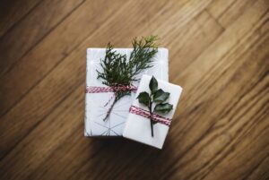 Zwei Weihnachtsgeschenke mit kleinen Zweigen dekoriert.