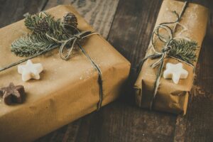 Zwei Weihnachtsgeschenke eingepackt in Packpapier mit Weihnachtsplätzchen und Tannenzweig.