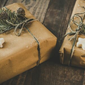 Zwei Weihnachtsgeschenke eingepackt in Packpapier mit Weihnachtsplätzchen und Tannenzweig.