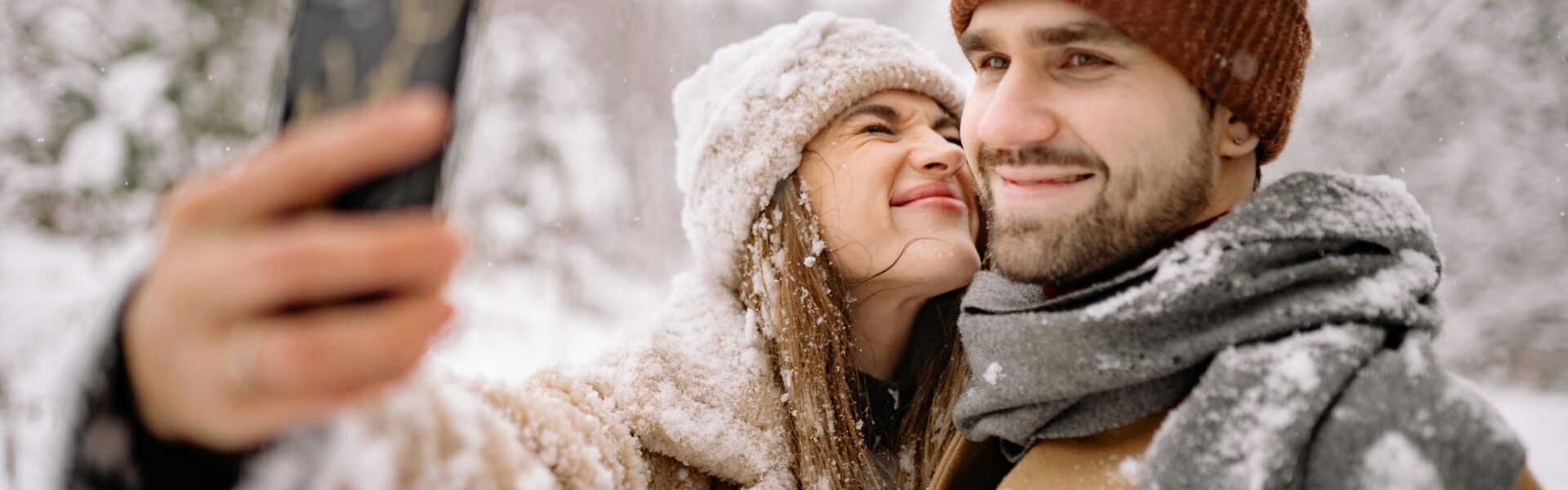 Frau und Mann im Schnee nehmen ein Selfie auf.